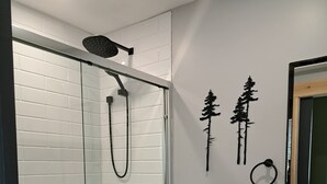 A modern bathroom with a glass-enclosed shower, a toilet, and a sink.
