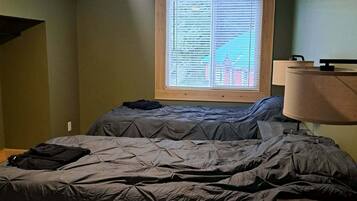 Un dormitorio con cama, ventana con persianas, ventilador de techo y lámpara.