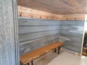 Una esquina de una habitación con un banco, paneles metálicos en la pared y techo de madera.
