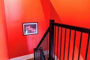 Eine Treppe mit schwarzer Geländer und einem Neonlicht an der Wand mit der Aufschrift 'good vibes only'.