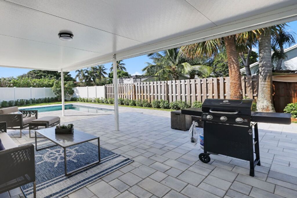 An outdoor patio with a grill, seating area, and a pool.