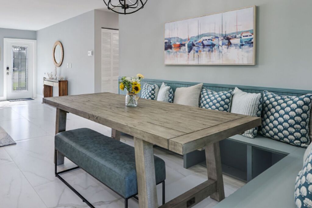 Un espace repas avec une table en bois, des bancs et un tableau accroché au mur.