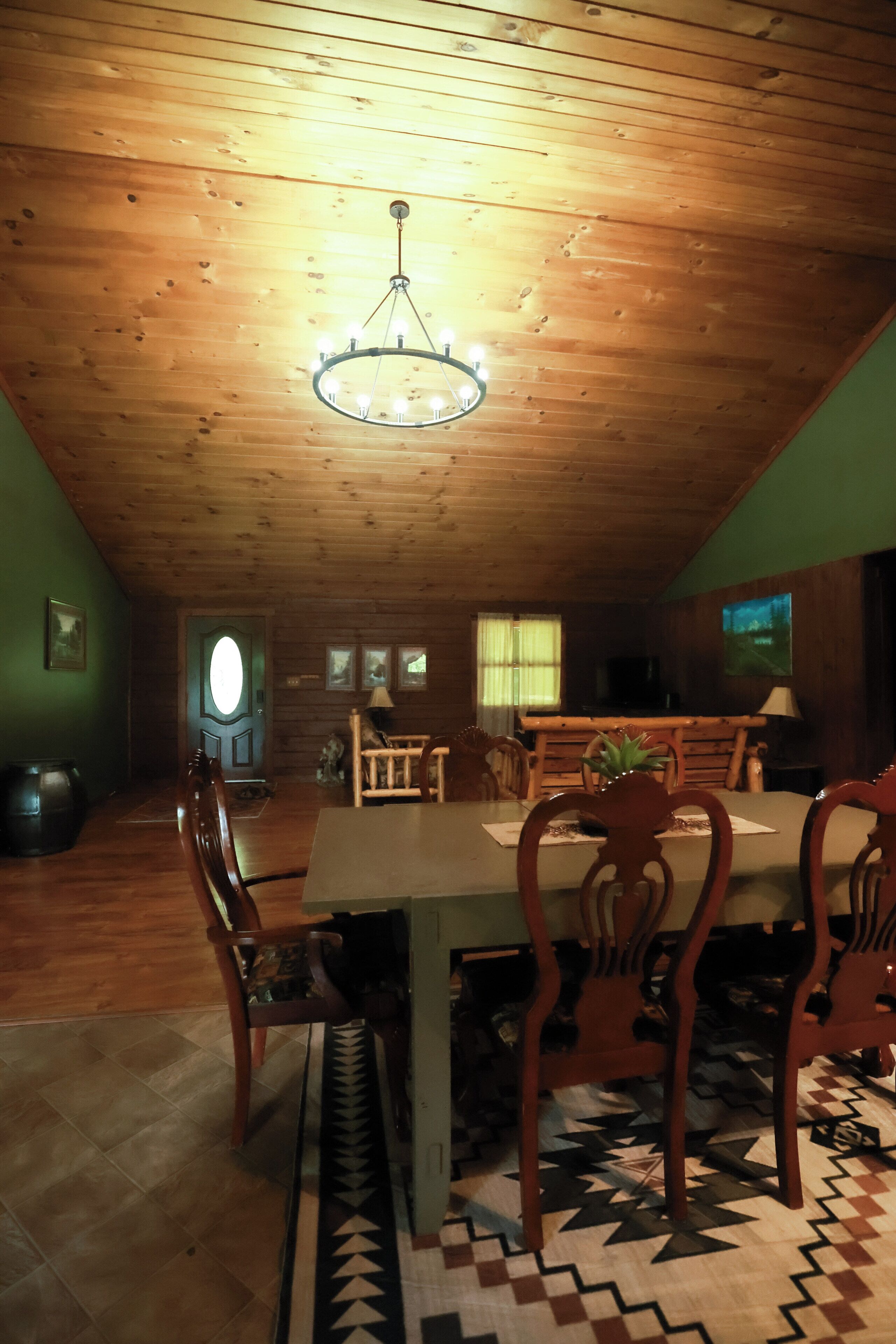 A dining area with a wooden ceiling, a chandelier, and a table set for four.