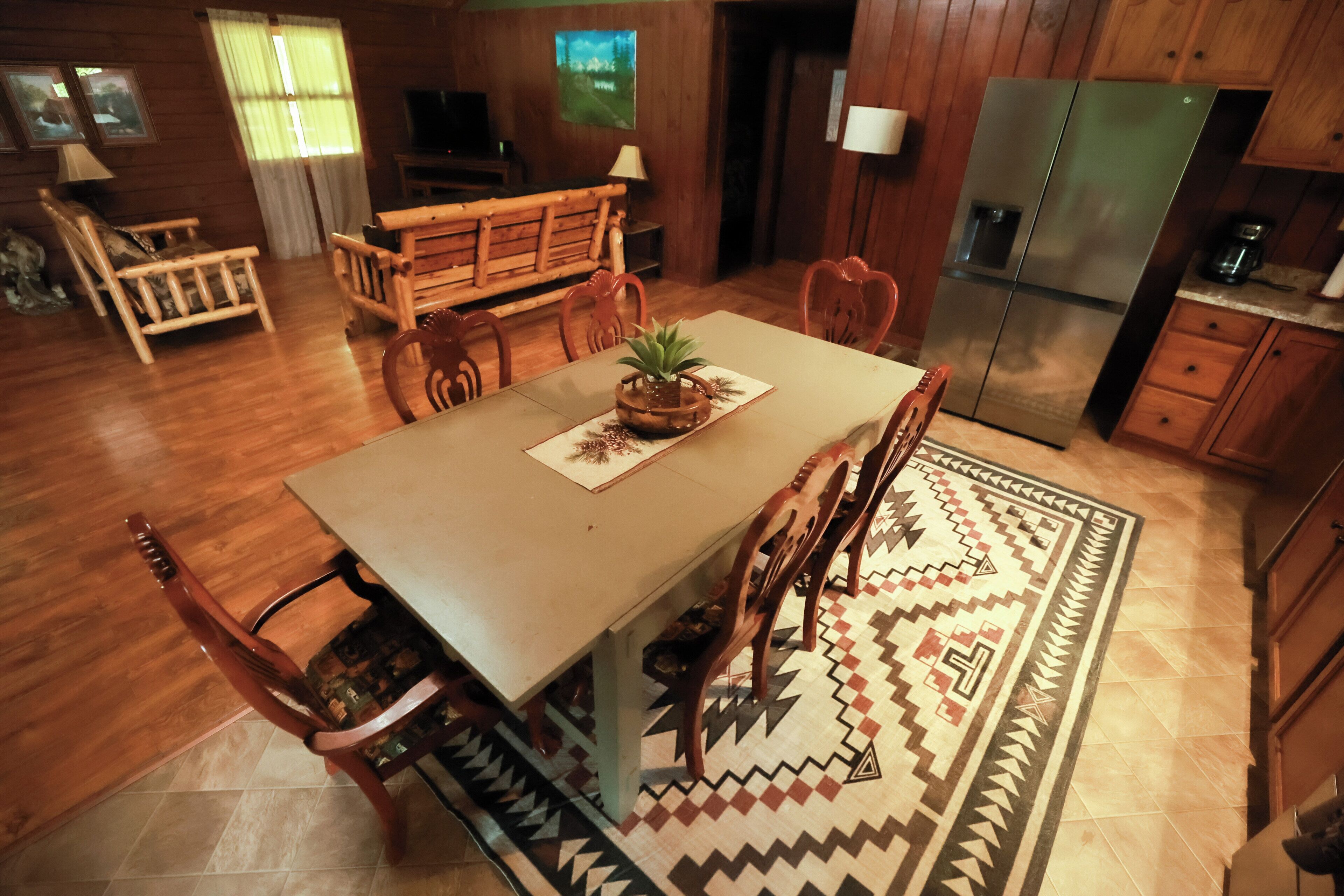 Un coin repas avec une table en bois, des chaises et un tapis à motifs.