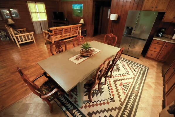 A dining area with a wooden table, chairs, and a patterned rug.