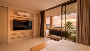 Ein modernes Hotelzimmer mit Flachbildfernseher, einem Bett, einem Balkon mit Meerblick und Deckenventilator.