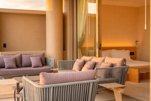A modern hotel room with a sofa, two armchairs, a bed, and a glass partition.