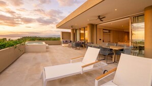 Eine moderne Terrasse im Freien mit Pool, Sitzgelegenheit und Blick auf den Ozean.