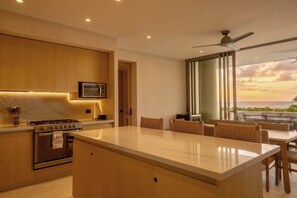 A modern kitchen with a central island, built-in appliances, and a view of the ocean at sunset. - Anera Apt with Plunge Pool Overlooking the Ocean (Playa Blanca)