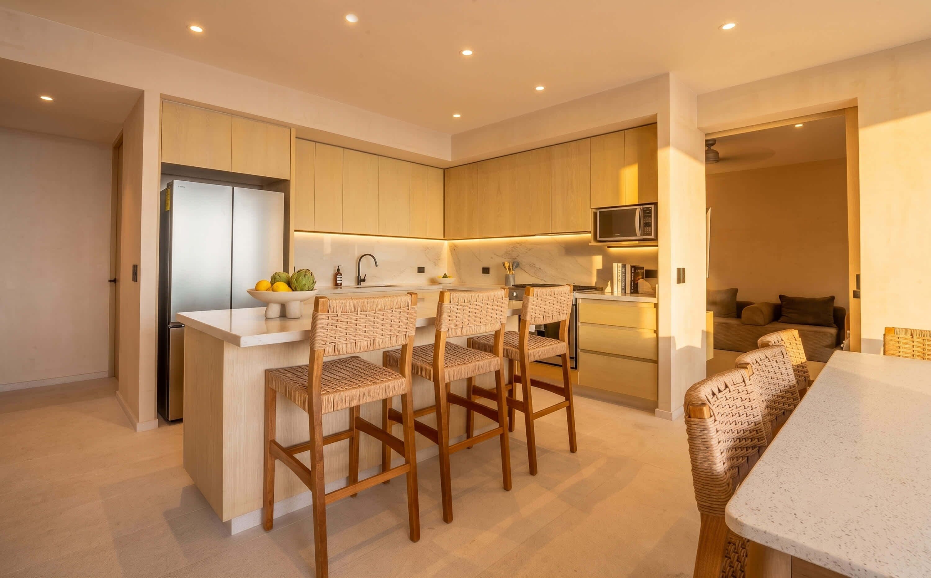 A modern kitchen with a central island, wooden chairs, and a dining table.