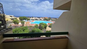 Vista de uma piscina rodeada por vegetação, com edifícios ao fundo.