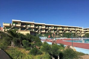 Ein mehrstöckiges Hotel mit Poolanlage, umgeben von viel Grün.