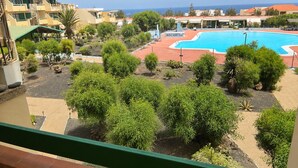 Piscina rodeada por vegetação e edifícios, com vista para o mar.