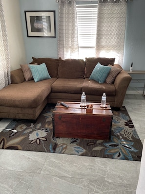 A living room with a brown sectional sofa, a wooden coffee table, and a patterned rug. - A quiet place to rest, regroup and reenergize! (Sarasota)