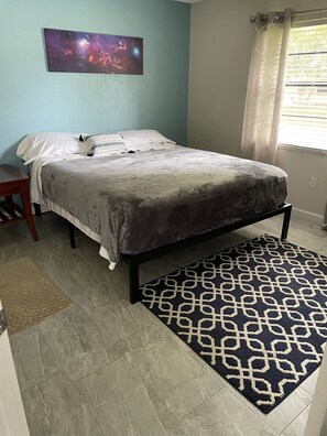 A bedroom with a bed, a nightstand, a patterned rug, and a wall-mounted picture. - A quiet place to rest, regroup and reenergize! (Sarasota)