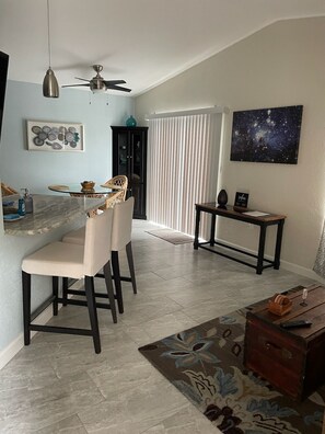 A dining area with a round table, chairs, a ceiling fan, and a wall-mounted light fixture. - A quiet place to rest, regroup and reenergize! (Sarasota)