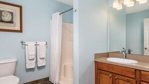 Un baño con inodoro, lavamanos, ducha y un perchero para toallas.