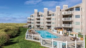 Un hotel de varios pisos con piscina, zona de estar exterior y vista a la playa.