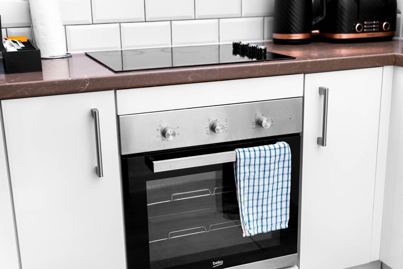 Una cocina equipada con horno empotrado, cafetera y dispensador de toallas de papel.