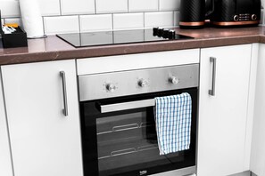 A kitchen with a built-in oven, a coffee maker, and a paper towel dispenser. - City Centre Apartment* 4 Guests* Jewellery Quarter (West Midlands)