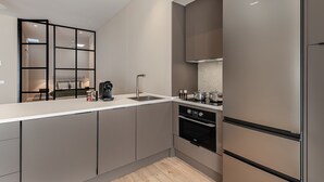 A modern kitchen with a built-in oven, a coffee machine, and a large refrigerator. - Waou Essence III Tétouan - Short-Term (Madrid)