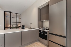 A modern kitchen with a built-in oven, a coffee machine, and a large refrigerator. - Waou Essence III Tétouan - Short-Term (Madrid)