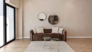 A modern living room with a brown sofa, two round mirrors, and two small tables with gold legs. - Waou Essence III Tétouan - Short-Term (Madrid)