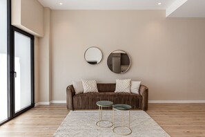 A modern living room with a brown sofa, two round mirrors, and two small tables with gold legs. - Waou Essence III Tétouan - Short-Term (Madrid)