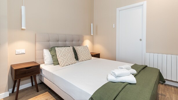 A bedroom with a bed, bedside tables, a radiator, and a door. - Waou Essence III Tétouan - Short-Term (Madrid)