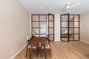 A room with a dining table, chairs, a ceiling fan, and a view through a glass partition. - Waou Essence III Tétouan - Short-Term (Madrid)