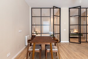 A modern interior with a dining area, a visible bed, and a bathroom in the background. - Waou Essence III Tétouan - Short-Term (Madrid)