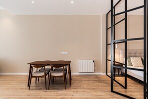 A room with a wooden table and chairs, a radiator, and a bed with a headboard. - Waou Essence III Tétouan - Short-Term (Madrid)