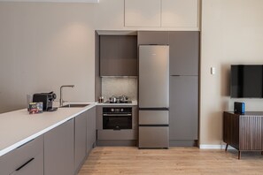 A modern kitchen with a built-in stove, a refrigerator, and a coffee maker. - Waou Essence III Tétouan - Short-Term (Madrid)