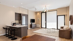 A modern kitchen with a central island, bar stools, a dining table, and a seating area with a sofa and armchairs. - Waou Essence III Tétouan - Short-Term (Madrid)
