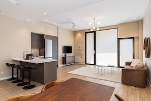 A modern kitchen with a central island, bar stools, a dining table, and a seating area with a sofa and armchairs. - Waou Essence III Tétouan - Short-Term (Madrid)