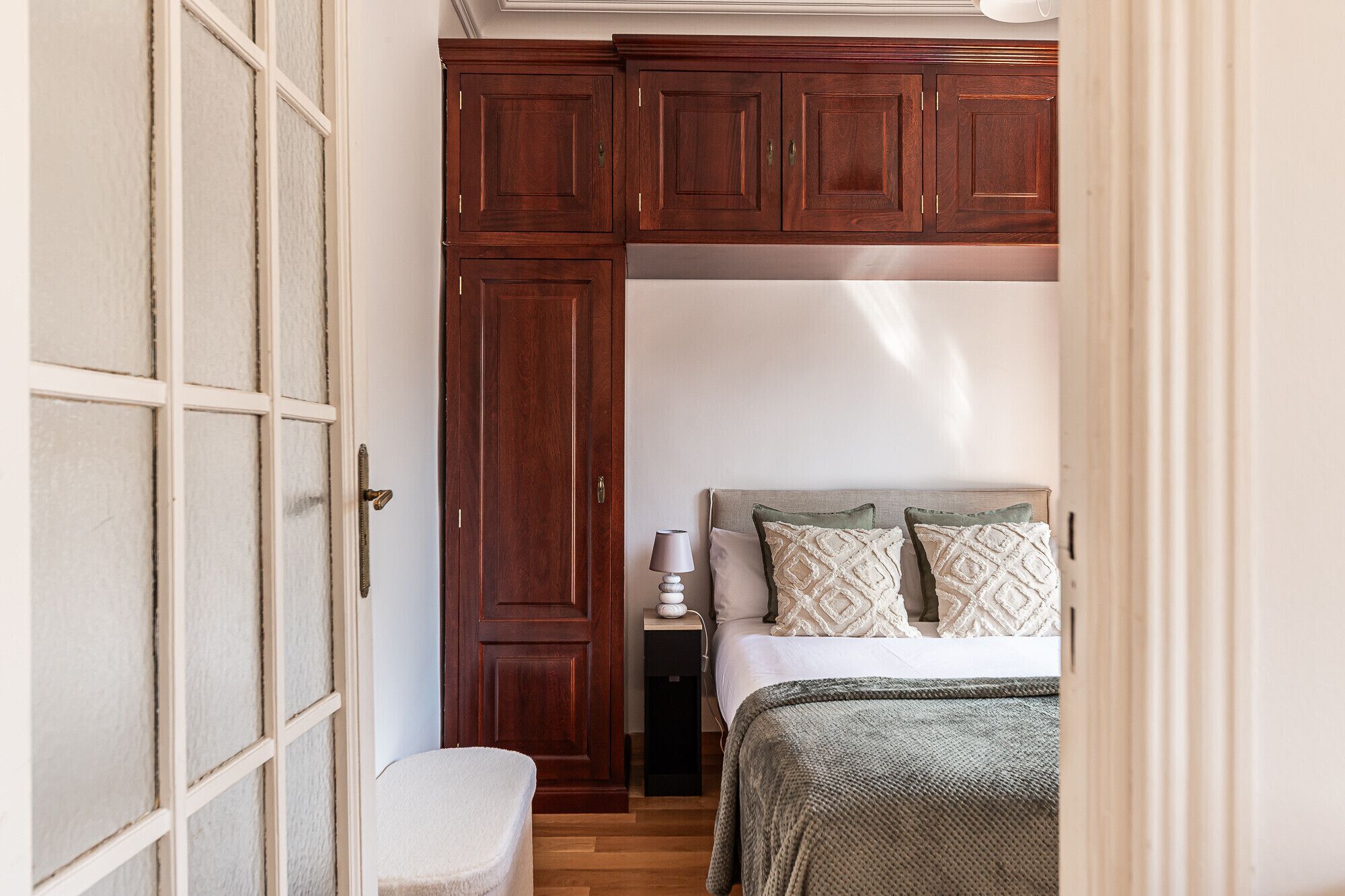 Une chambre à coucher avec un lit, une table de chevet, une lampe et une armoire.