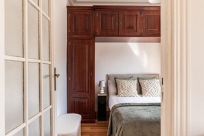 A bedroom with a bed, bedside table, lamp, and a wardrobe. - Waou Sol XII - Short-Term Rental (Madrid)