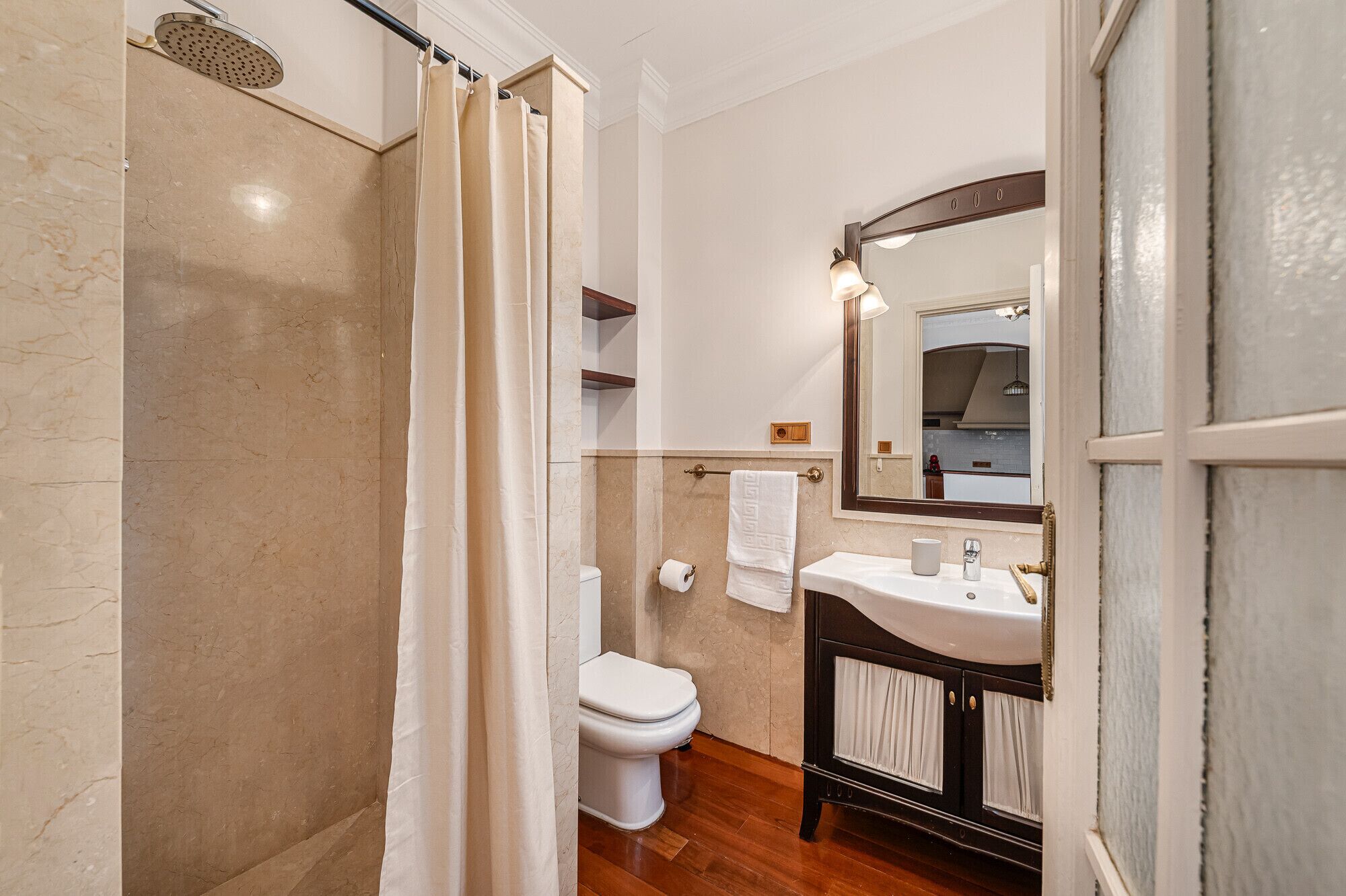 Een badkamer met douche, toilet, wastafel en spiegel.