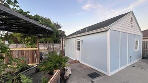 A small, single-story building with a gabled roof, a front door, and a small porch area. - Cozy 1-bedroom guest suite in lovely Corpus Christi with AC and kitchenette. (Corpus Christi)
