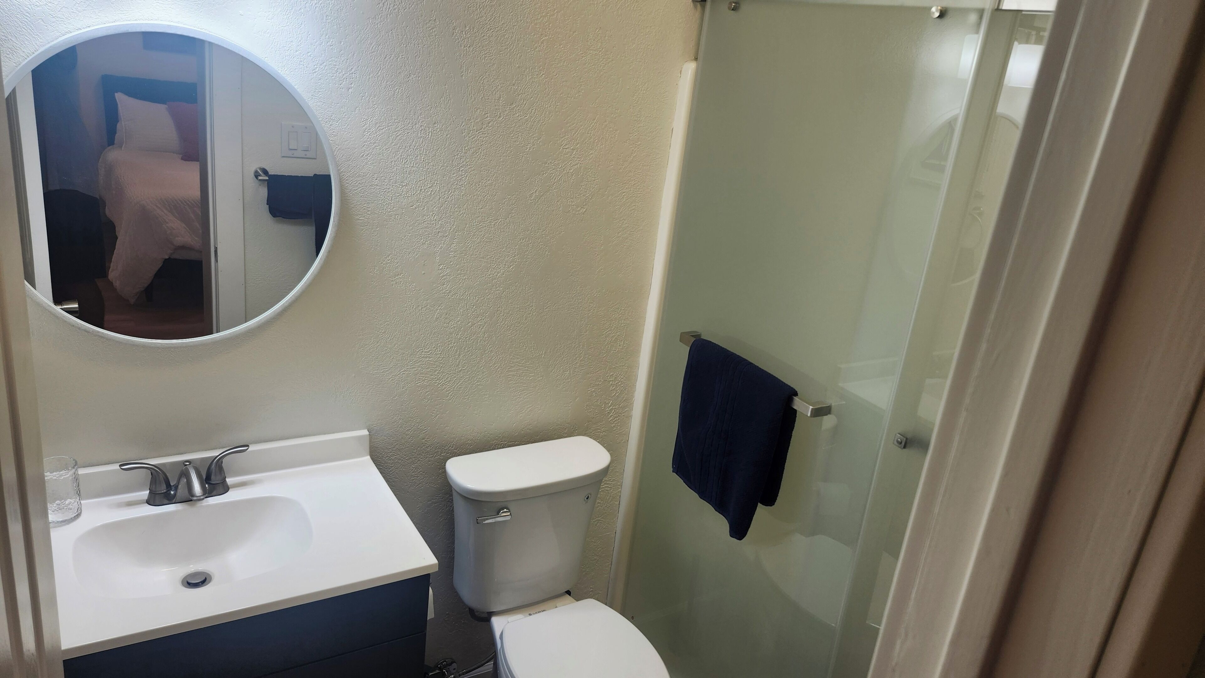 Ein Badezimmer mit einem weißen Waschbecken, einer Toilette und einer Duschkabine aus Glas.