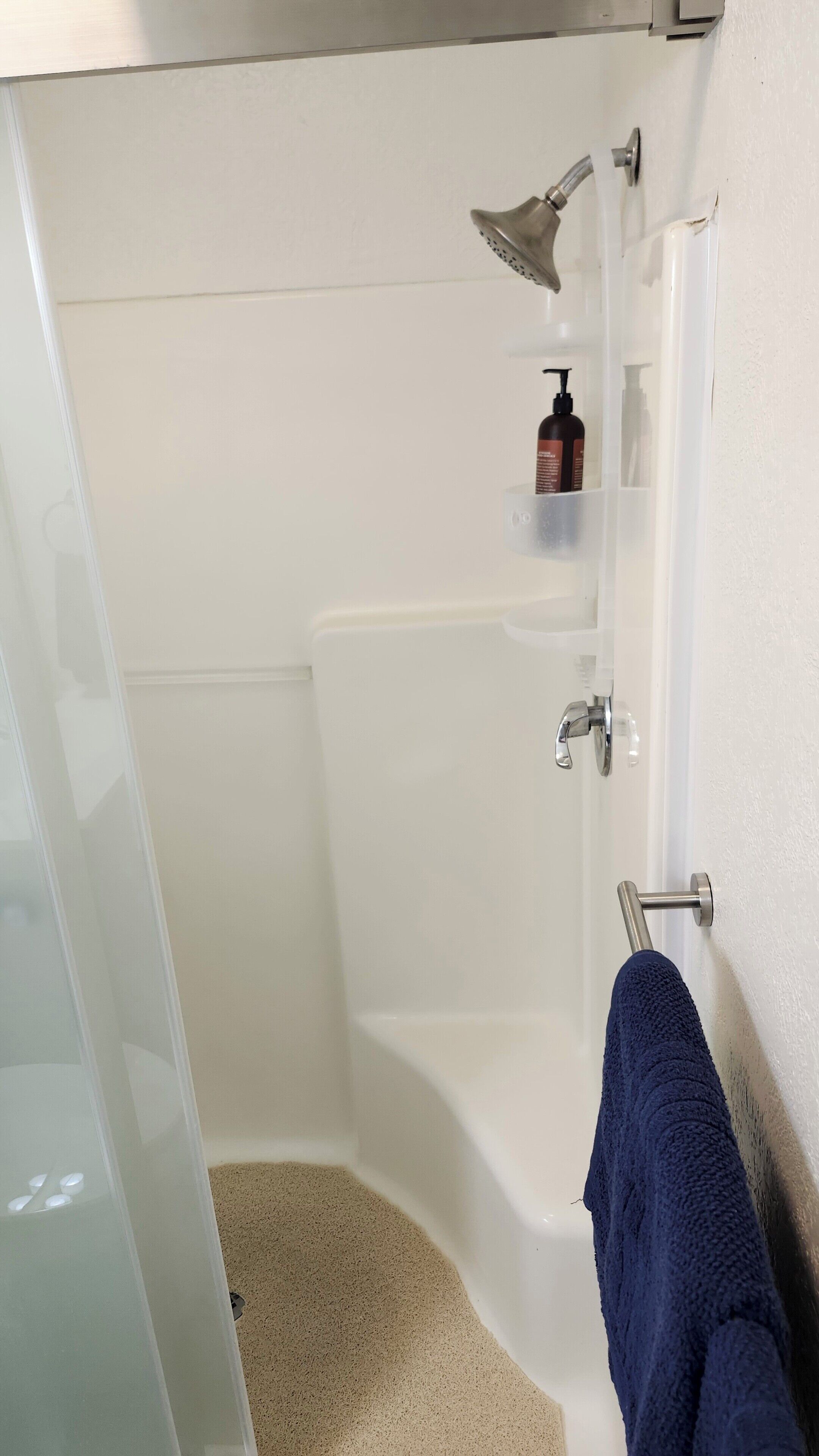 Ein Badezimmer mit einer Badewanne, einer Duschbrause, einem Handtuchhalter und einer Shampooflasche.