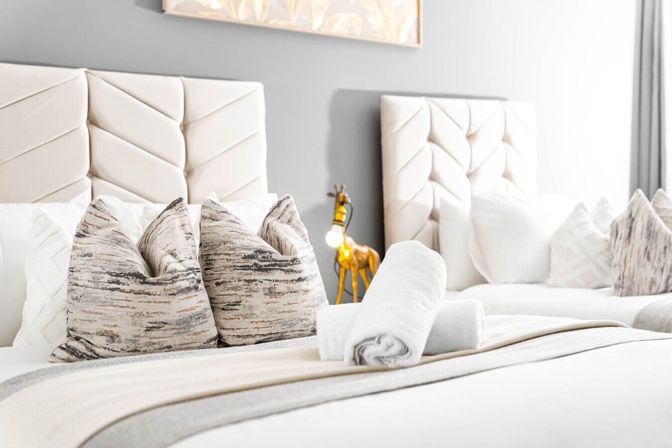 A hotel room with a large bed, multiple pillows, a decorative deer figurine, and a wall-mounted artwork.