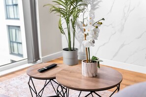 A room with two round tables, a potted orchid, and a remote control on one table. - Stylish Apartment * Sleep 4 * Parking * Netflix (West Midlands)