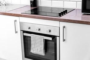 A kitchen with a built-in oven, a stovetop, and a microwave. - Stylish Apartment* Jewellery Q * Parking* Netflix (West Midlands)