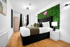Ein modernes Schlafzimmer mit Bett, Nachttisch und einer grünen Wandgestaltung.
