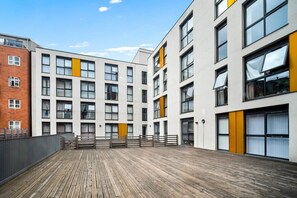 A modern building with multiple floors, large windows, and a wooden deck area. - Stylish Apartment* Jewellery Q * Parking* Netflix (West Midlands)