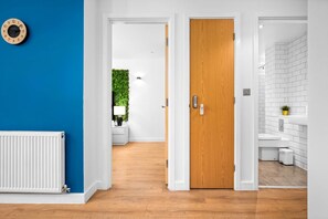 Un corridoio con una porta in legno, un termosifone bianco e una parete blu.