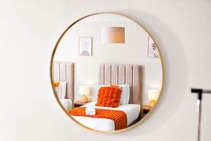 Ein Hotelzimmer mit Bett, Nachttischen, einer Lampe und einem Spiegel.