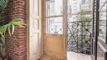 Ein Zimmer mit Backsteinwand, Holztür und Fenster mit einem schmiedeeisernen Balkon.