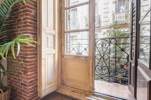 Ein Zimmer mit Backsteinwand, Holztür und Fenster mit einem schmiedeeisernen Balkon.